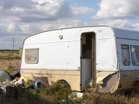 Old caravan surrounded by litter